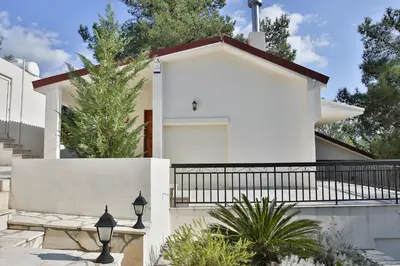 a white house with a fence and trees at Nestor Hillside House by TrulyCyprus in Moniatis