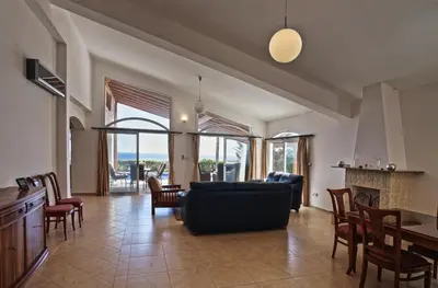a living room with a couch and a table and chairs at Sunset Cliff Villa Panoramic Sea Views Private Heated Pool Included in Pissouri