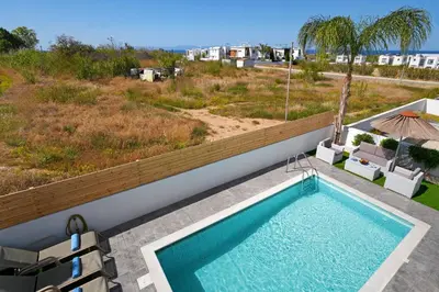 a swimming pool on the side of a house at Villa Carmen in Protaras