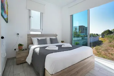 a bedroom with a large bed and a large window at Villa Carmen in Protaras