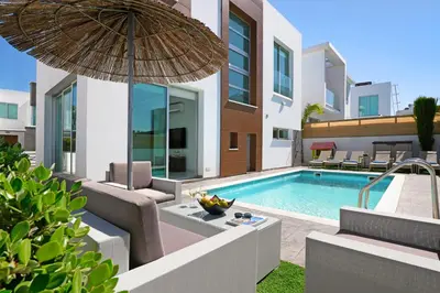 a villa with a swimming pool and an umbrella at Villa Carmen in Protaras