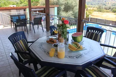 a table with food and orange juice on a balcony at Yiannos House in Evrykhou