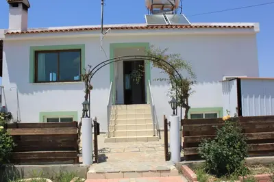 a white house with an open door with a wooden fence at Yiannos House in Evrykhou