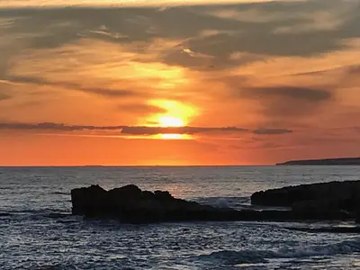 a sunset over the ocean with rocks in the water at Villa Julia in Ayia Napa