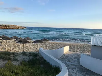 a sandy beach with umbrellas and the ocean at Villa Julia in Ayia Napa
