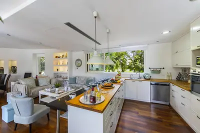 a kitchen and living room with white cabinets and a table at Larnaca Villa Marisol Kiti in Larnaka