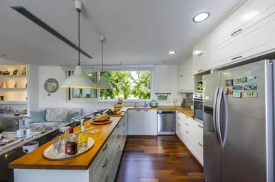 a large kitchen with white cabinets and a wooden floor at Larnaca Villa Marisol Kiti in Larnaka