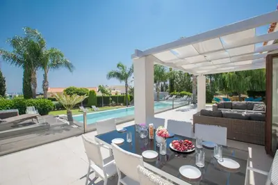 a patio with a table and chairs and a pool at Oscar Domain Villa in Protaras