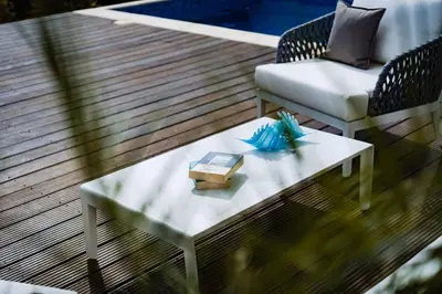a coffee table with a book and a chair on a deck at Atlantis Gardens in Mazotos