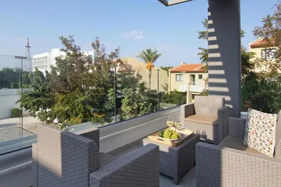 a balcony with wicker chairs and a table with wine glasses at Villa Maritime in Protaras