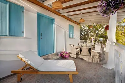 a porch with a white chair and a table at Cottage Houses in Pendakomo