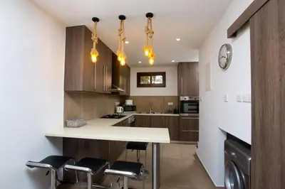a kitchen with wooden cabinets and a white table and chairs at Galatex Beach Living by TrulyCyprus in Limassol