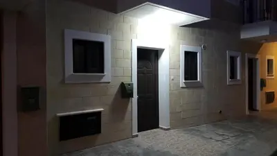a hallway with a black door in a brick wall at CHRIS'S KYKLADES HOLIDAY APARTMENT in Paralimni