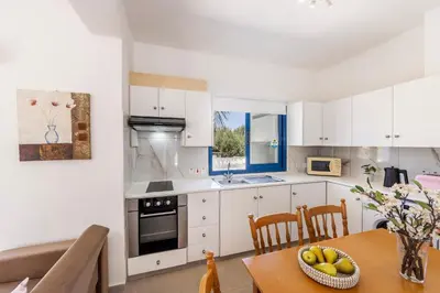 a kitchen with white cabinets and a table with a bowl of fruit at Flouressia Gardens in Protaras