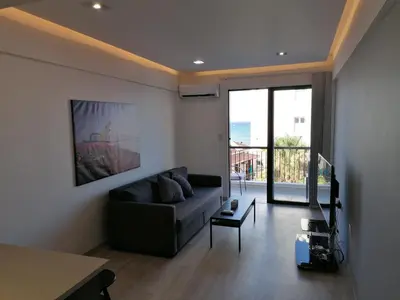 a living room with a couch and a large window at Must Stay - Finikoudes Seaview in Larnaka