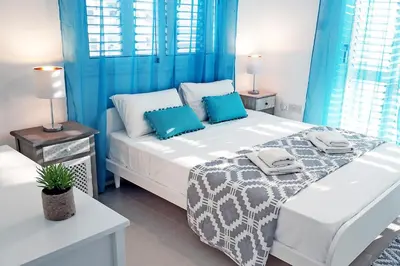 a bedroom with a large bed with blue curtains at Nissini Nero, 3 bedroom villa with private pool, 5 min to the beach in Ayia Napa