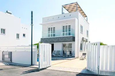 a white house with a fence in front of it at Nissini Nero, 3 bedroom villa with private pool, 5 min to the beach in Ayia Napa