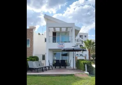 a white house with a table and an umbrella at Villa Sorelle in Protaras