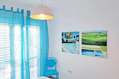 a room with two pictures on the wall and a blue chair at Nissini Blanco, 3 bedroom villa with private pool, 5 min to the beach in Ayia Napa
