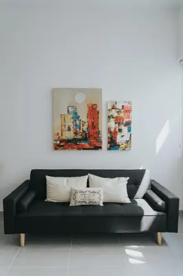 a black couch in a room with two paintings on the wall at Prima Gardens City Studios in Larnaka