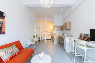 a living room with an orange couch and a kitchen at Prima Gardens City Studios in Larnaka