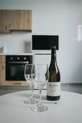 a bottle of wine and two wine glasses on a counter at Prima Gardens City Studios in Larnaka