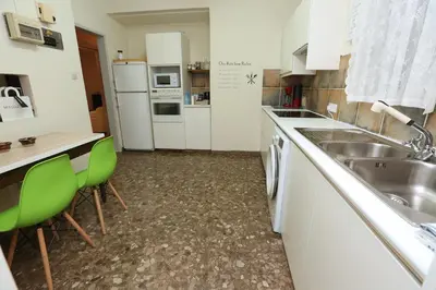 a kitchen with a sink and a counter with green chairs at The Bridge-House Apartment in Nicosia