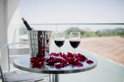 two glasses of wine on a table with roses at Twins Apartments in Kato Pyrgos