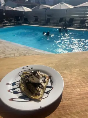 a plate of food on a table next to a swimming pool at Twins Apartments in Kato Pyrgos