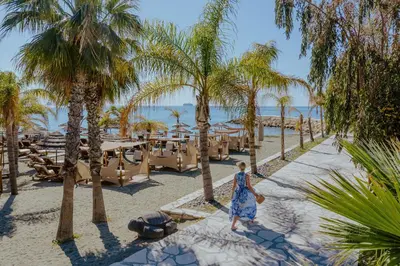 a woman walking down a path on the beach with palm trees at Four Seasons Hotel in Limassol