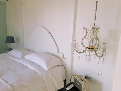 a white bedroom with a bed and a chandelier at CASAVERO in Voroklini
