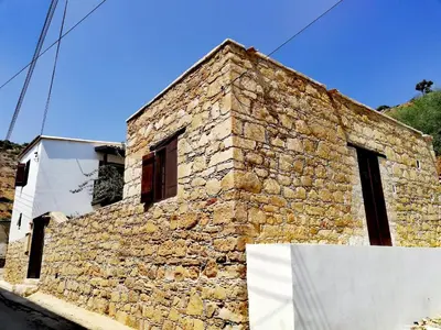 a stone building with two windows on a street at CASAVERO in Voroklini