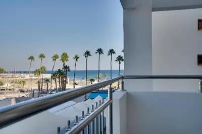a balcony with a view of the beach and palm trees at AirBnSea City Centre Side Sea view Apartments in Larnaka