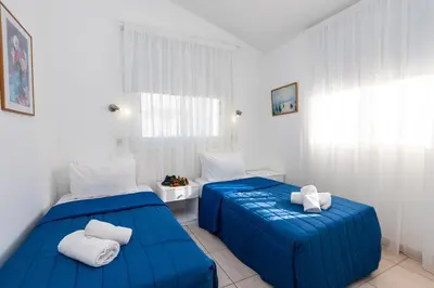two beds in a white room with blue sheets at Fig Tree Z Holiday Resort in Paralimni
