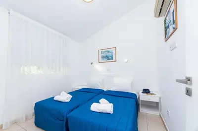 two beds in a white room with towels on them at Fig Tree Z Holiday Resort in Paralimni