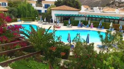 a swimming pool with umbrellas and people sitting around it at Hylatio Tourist Village in Pissouri
