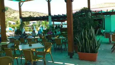 a restaurant with tables and chairs and people sitting at tables at Hylatio Tourist Village in Pissouri