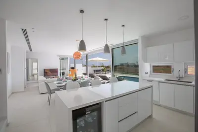a kitchen with white cabinets and a living room at Villa Alana in Protaras