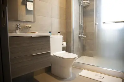a bathroom with a toilet and a sink and a shower at Jimmy's Suites in Larnaka