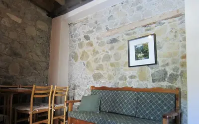 a room with a stone wall with a couch and chairs at Ayios Andronikos Agrotourism House in Kalopanayiotis