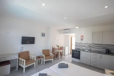 a kitchen with white cabinets and chairs and a table at Pavlinia Hotel & Apartments in Ayia Napa