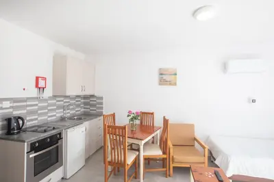 a kitchen with a table and chairs and a bed at Pavlinia Hotel & Apartments in Ayia Napa