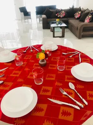 a table with white plates and glasses on a red table cloth at Mobina Villas in Larnaka