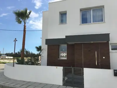 a white building with a palm tree in front of it at Mobina Villas in Larnaka