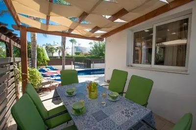 a table and green chairs on a patio with a table at Villa Papantonia in Protaras