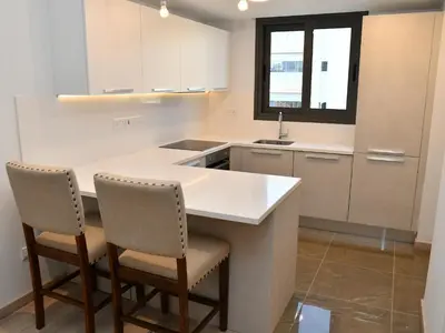 a kitchen with a white counter and two chairs at BAZ TOWER in Nicosia
