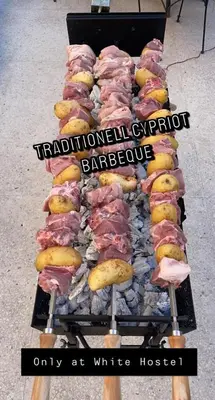 a grill with many different types of meat on it at White Hostel in Limassol