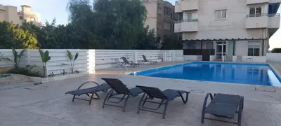 a swimming pool with chairs next to a building at Palm beach 14 in Limassol