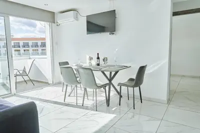 a white dining room with a table and chairs at Nissi Avenue Suites in Ayia Napa