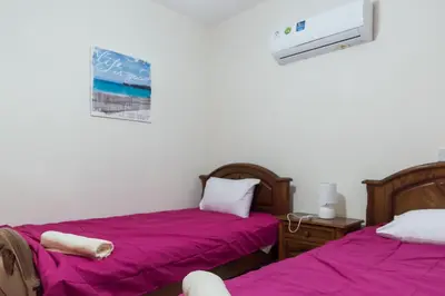 two beds in a room with purple sheets at EURO CARISSA FLAT 101 in Larnaka